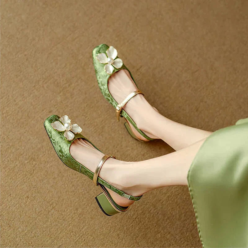 Female wearing pearl flower slingback heels on a plain background.