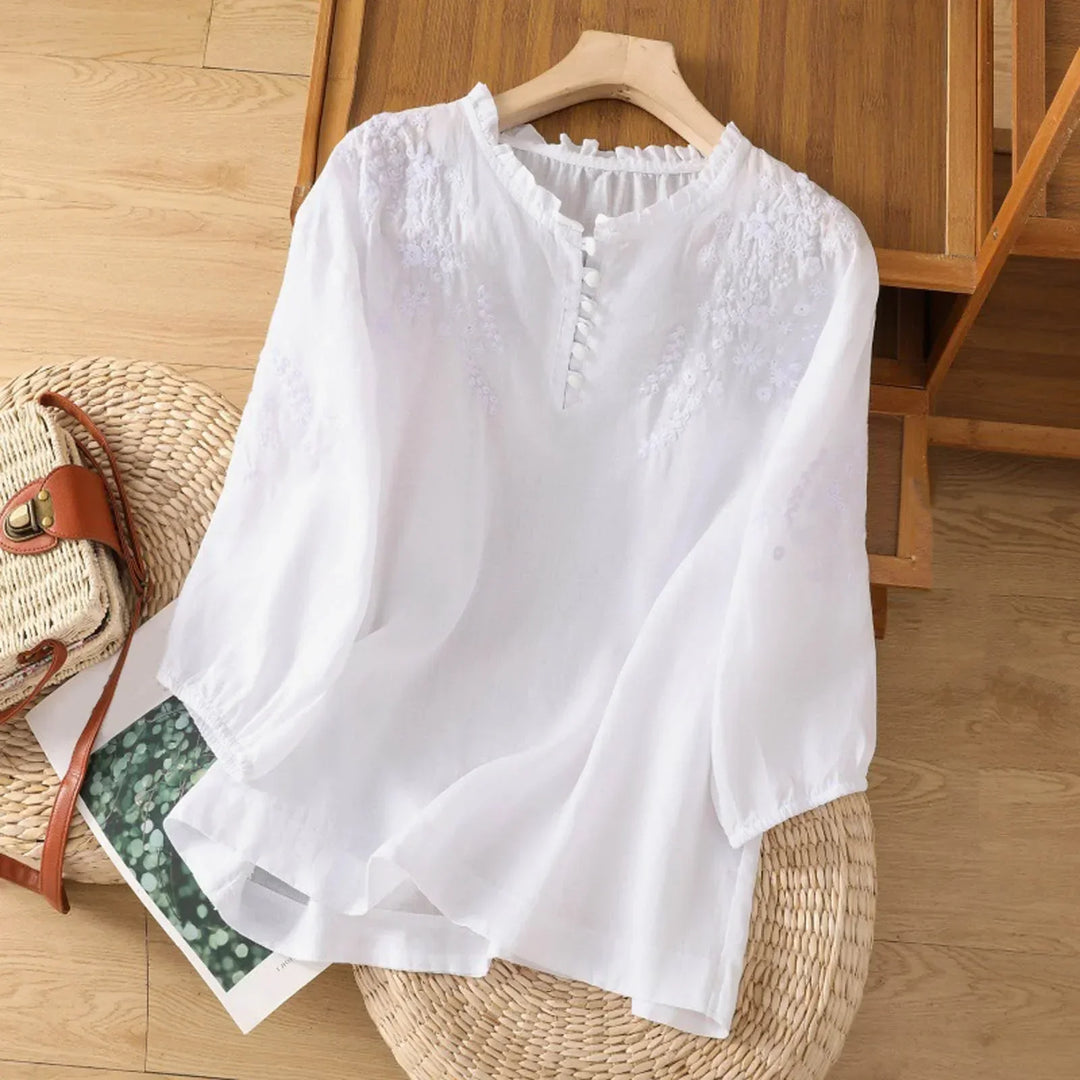 A classic embroidered blouse with a relaxed silhouette on a plain background.