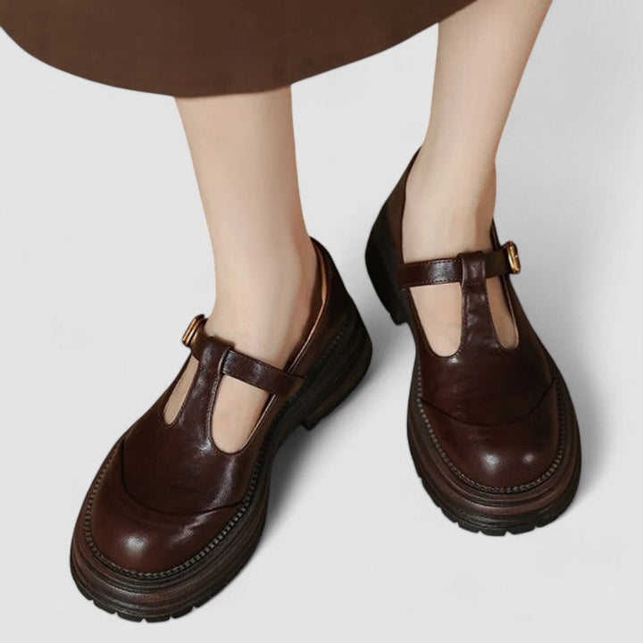 Woman wearing black Mary Jane shoes on a plain background.