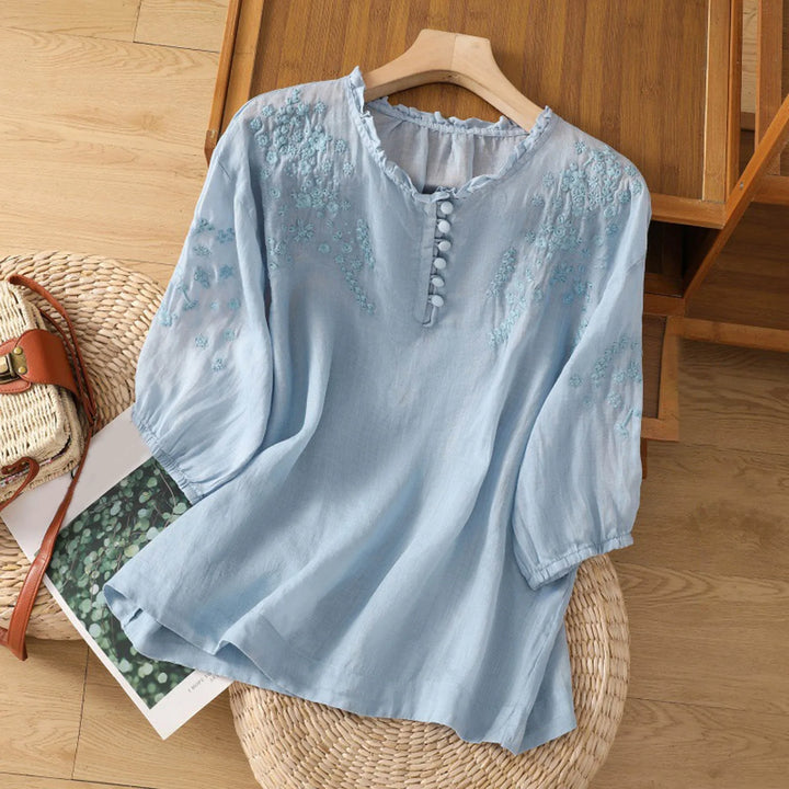 An embroidered button-front blouse against a plain background.