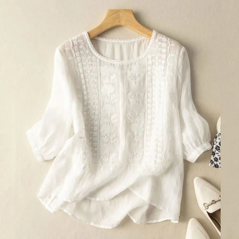 An embroidered blouse with a relaxed fit against a plain background.