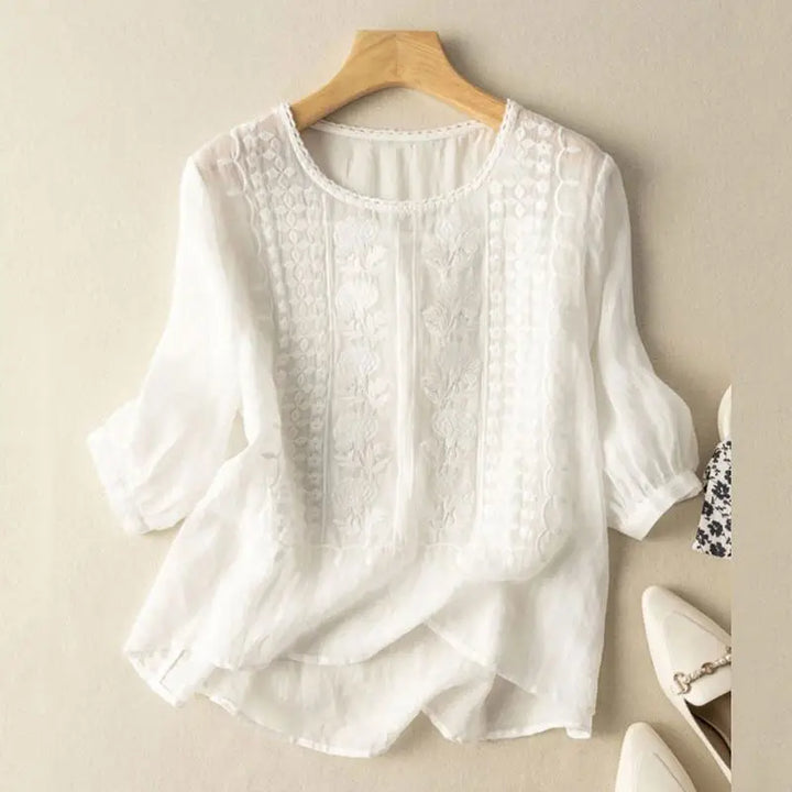 An embroidered blouse with a relaxed fit against a plain background.