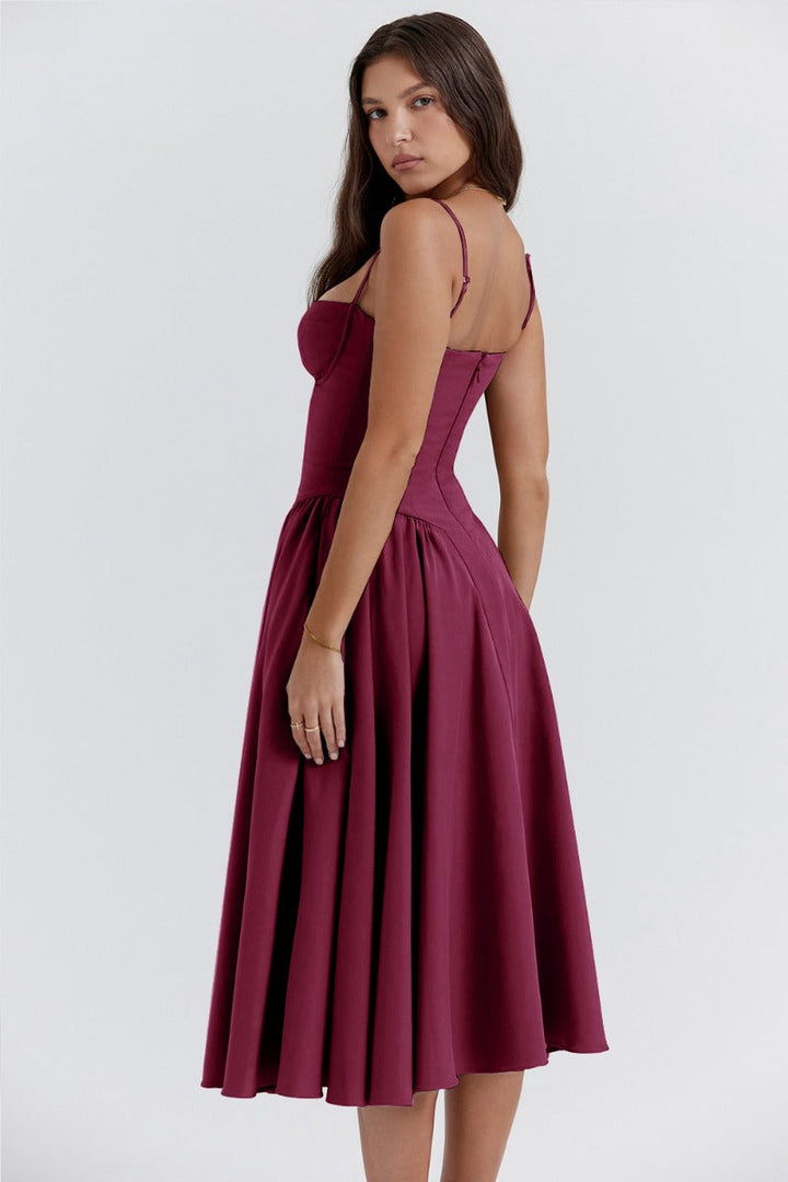 Woman wearing a soft pleated midi dress with a fitted waist on a plain background.