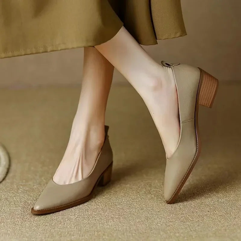 Woman wearing pointed block heel pumps on a plain background.