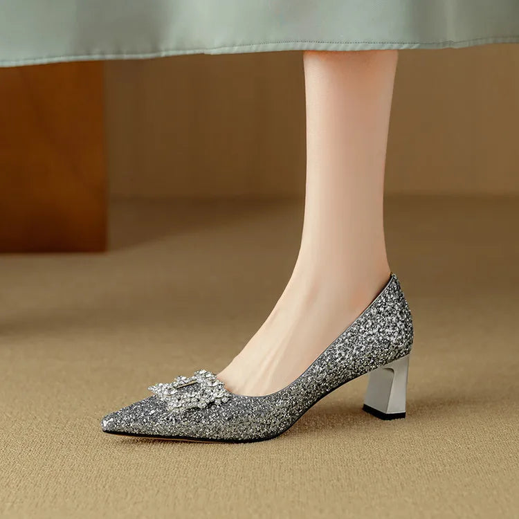 Female model wearing shimmer block heel shoes with elegant pointed toes on a plain background.