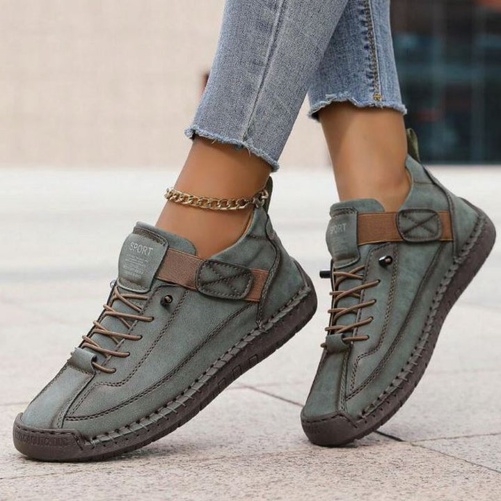 Woman wearing lace-up trainers with a clean and understated appearance on a plain background.