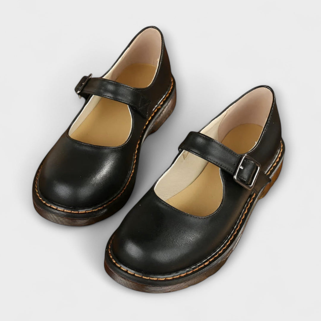 Female model wearing elegant strap shoes on a plain background.