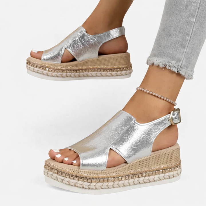 Model wearing espadrille platform wedge sandals with side cutouts on a plain background.
