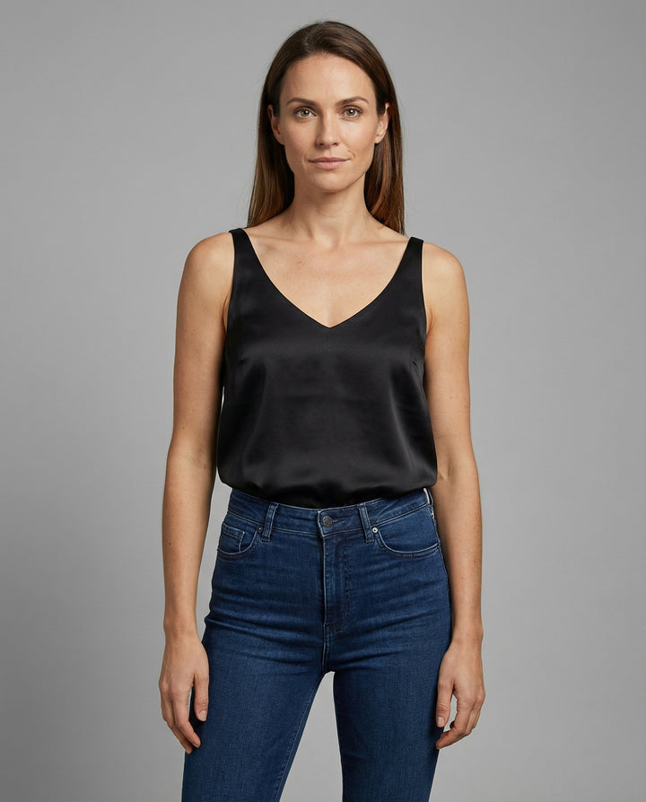 Woman wearing a silk tank top against a plain background.