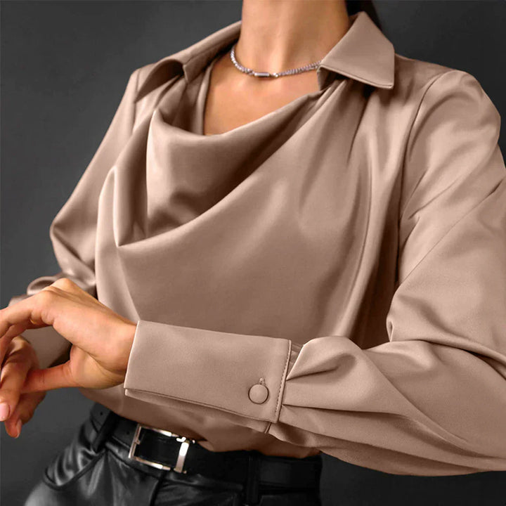 Female model wearing a draped neckline blouse on a plain background.