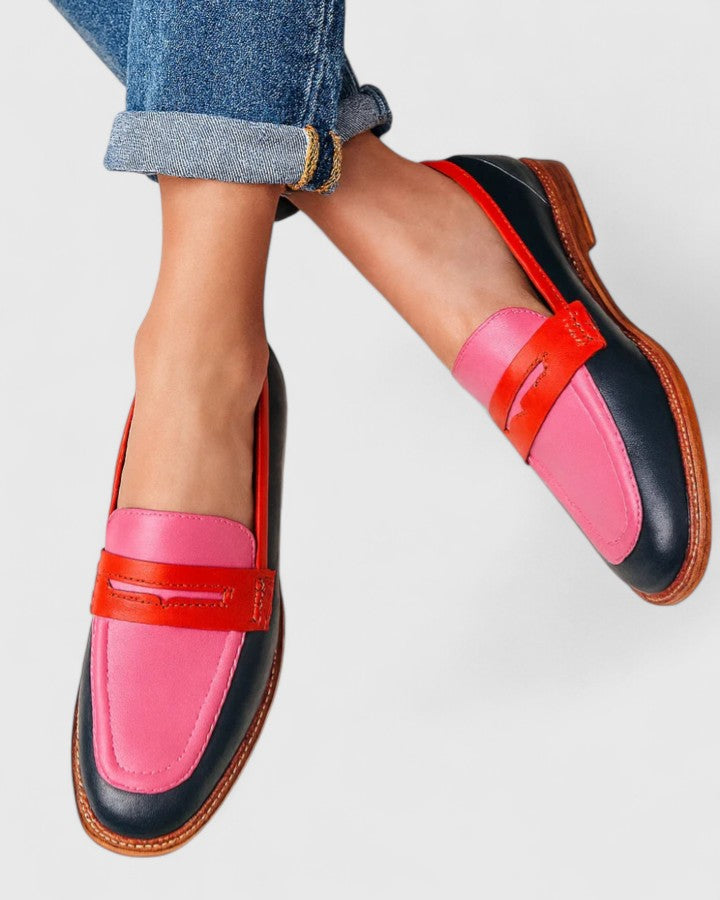 Woman wearing elegant loafers against a plain background.