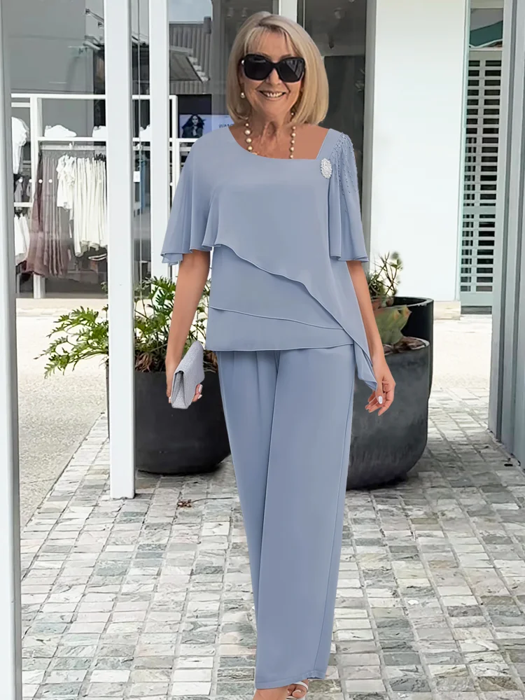 Female model wearing a women’s two piece set with an asymmetric top and wide leg pants on a plain background.