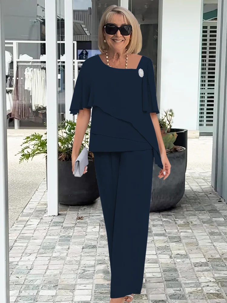 Woman modeling a matching blouse and wide leg pants outfit against a plain background.