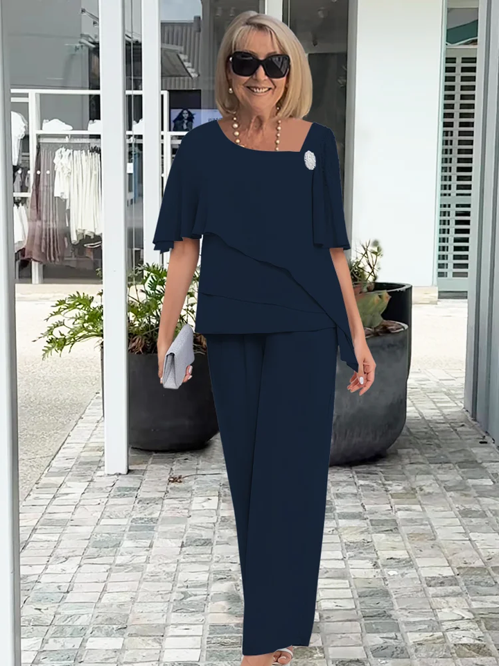 Woman modeling a matching blouse and wide leg pants outfit against a plain background.