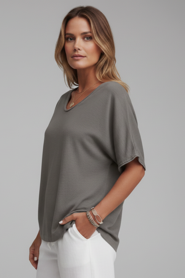 Woman styled in a relaxed round neck blouse against a plain background