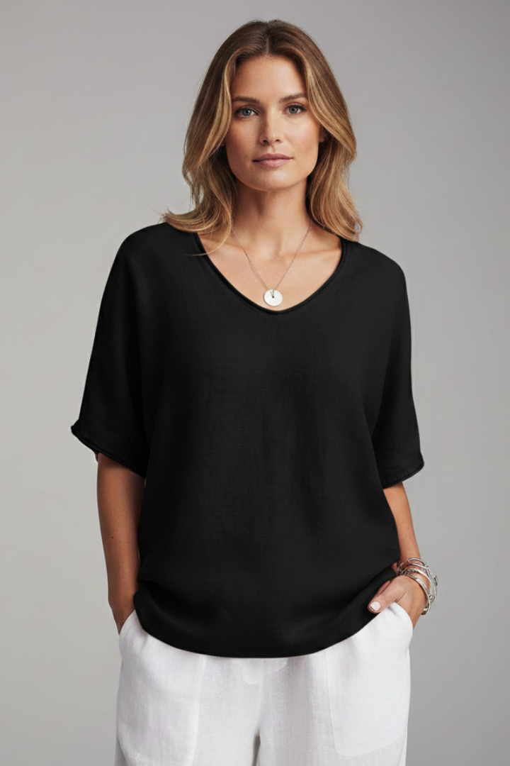 Woman wearing a flowy short sleeve blouse on a plain backdrop