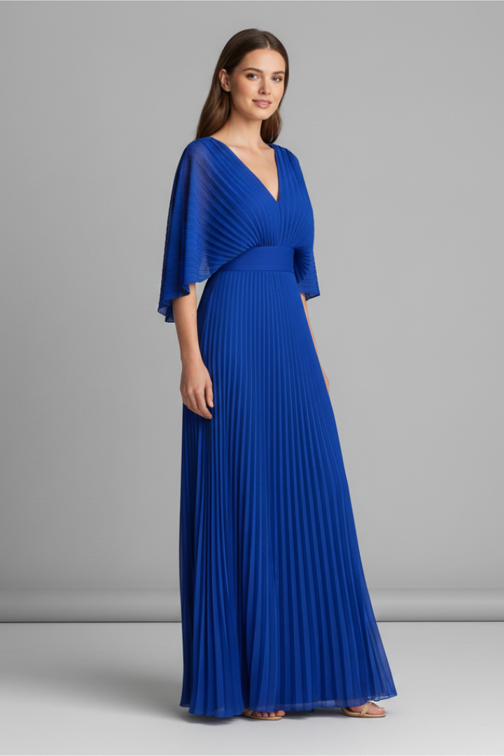 Woman in a long sleeve dress with a defined waist seam and flowing pleated skirt on a plain background.