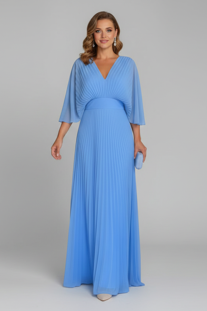 Female model showcasing a plain long dress with vertical pleats from waist to hem on a plain background.