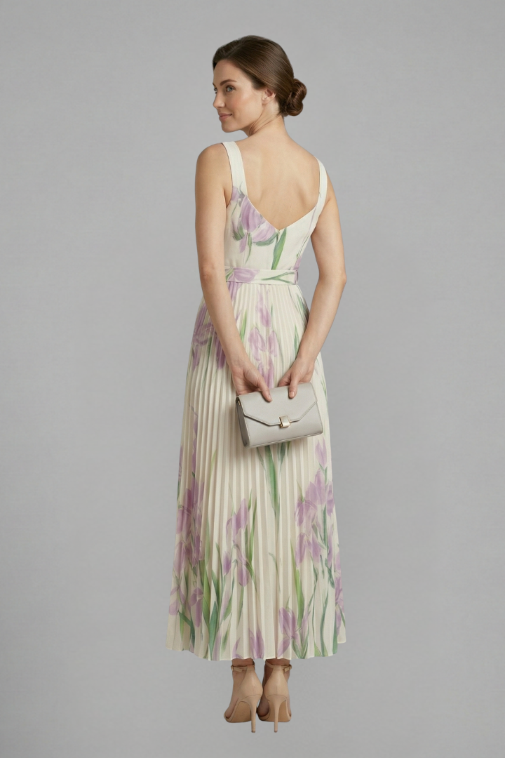 Woman wearing a floral pleated maxi dress with wide shoulder straps against a plain background.