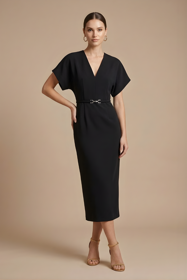 Female standing in a deep V neck midi dress with a streamlined shape on a plain background.