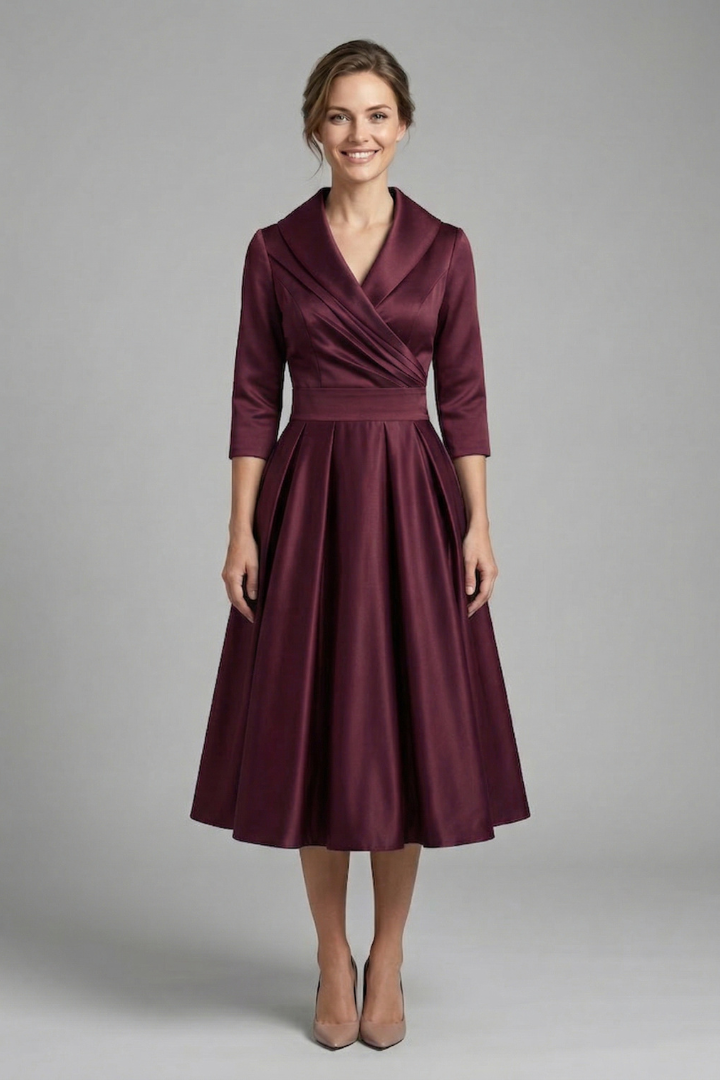 Female model wearing a modest midi dress with long sleeves and pleated volume on a plain background.