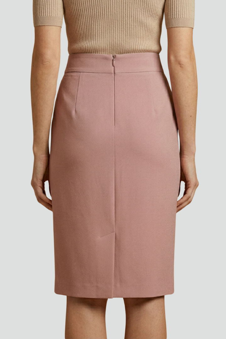 Woman in a fitted high waist midi skirt styled with a simple top on a plain background.