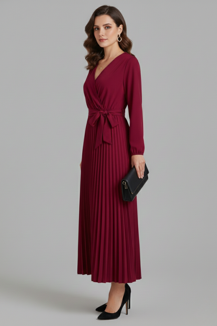 Woman in a flowing maxi dress featuring a deep V-neckline and long sleeves on a plain background.