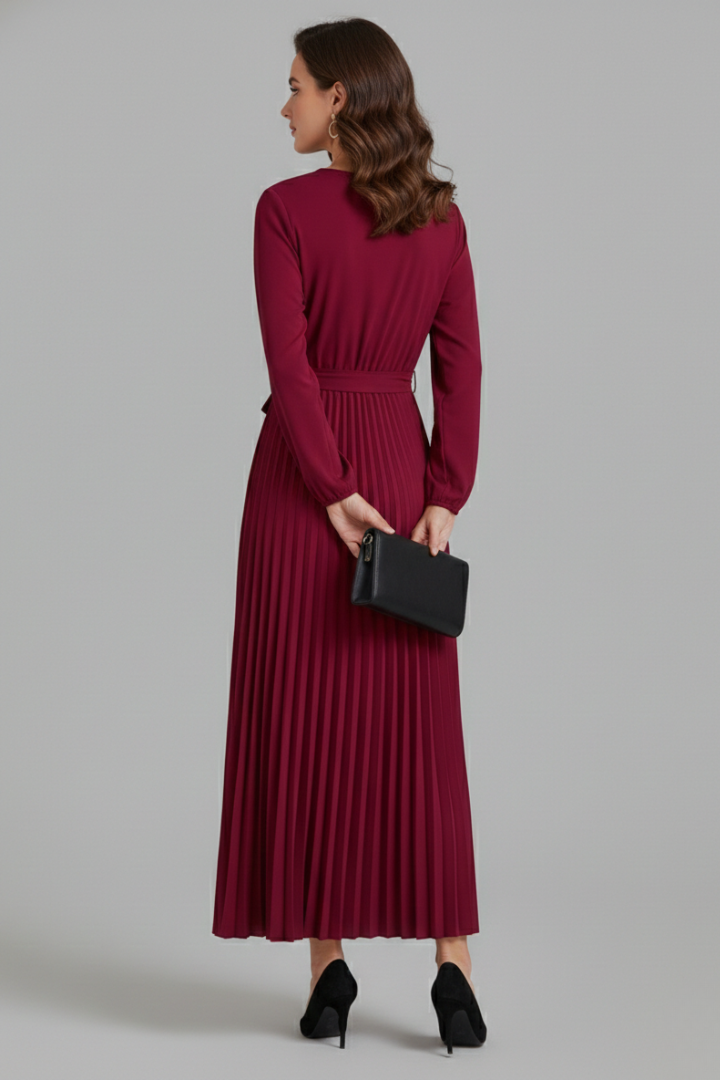 Female model showcasing a pleated maxi dress with an adjustable waist tie and long sleeves.