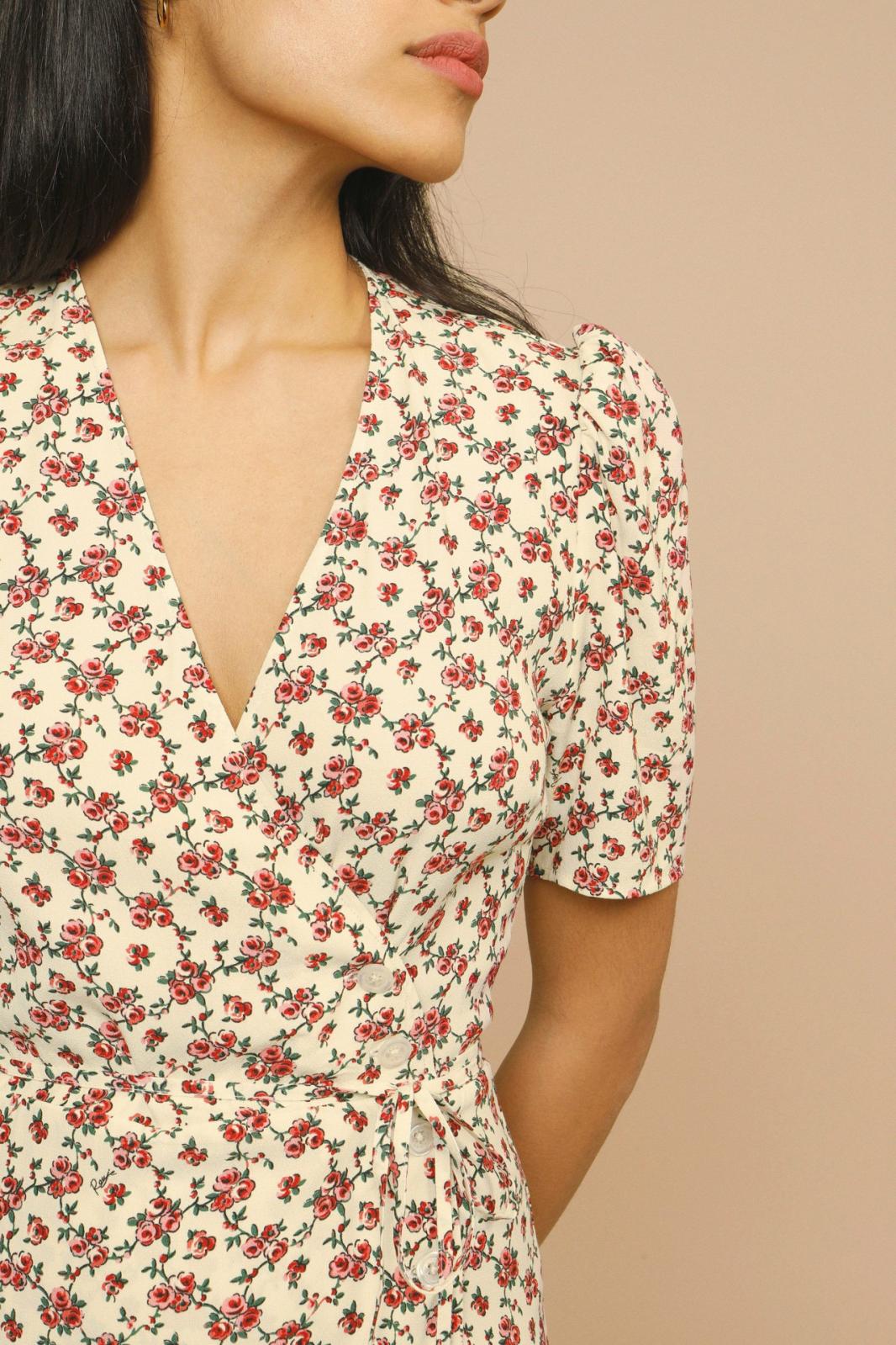 Female model showcasing a V-neck floral midi dress with elegant movement on a plain background.