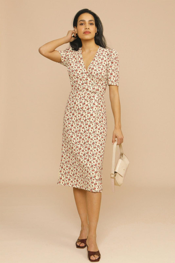 Female model wearing a floral midi dress with a V-neck on a plain background.