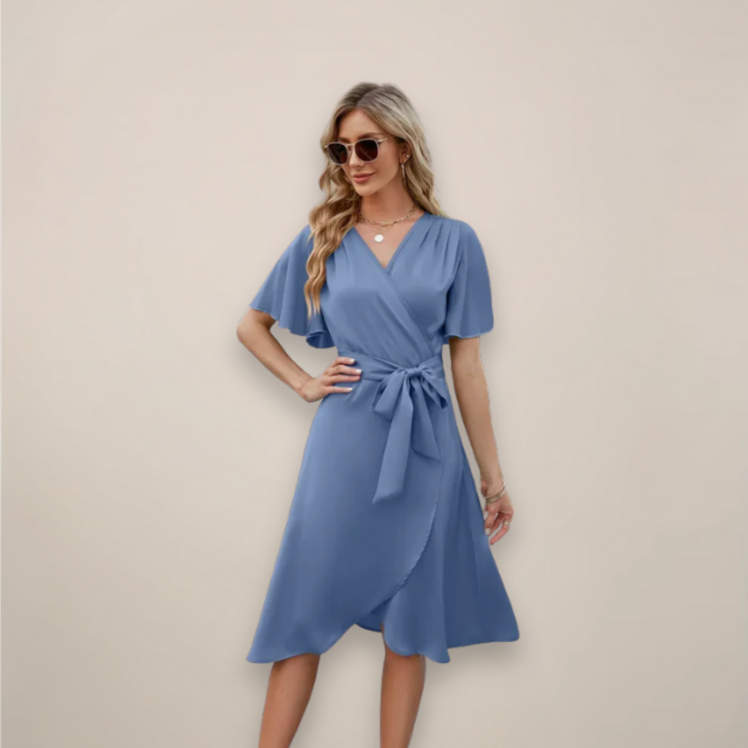 Woman wearing a midi wrap dress with a tie waist against a plain background.