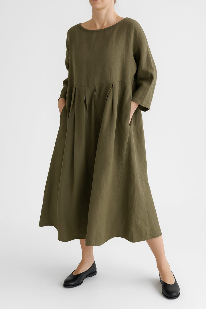 Woman wearing a relaxed-fit midi dress with a flowing silhouette on a plain background.