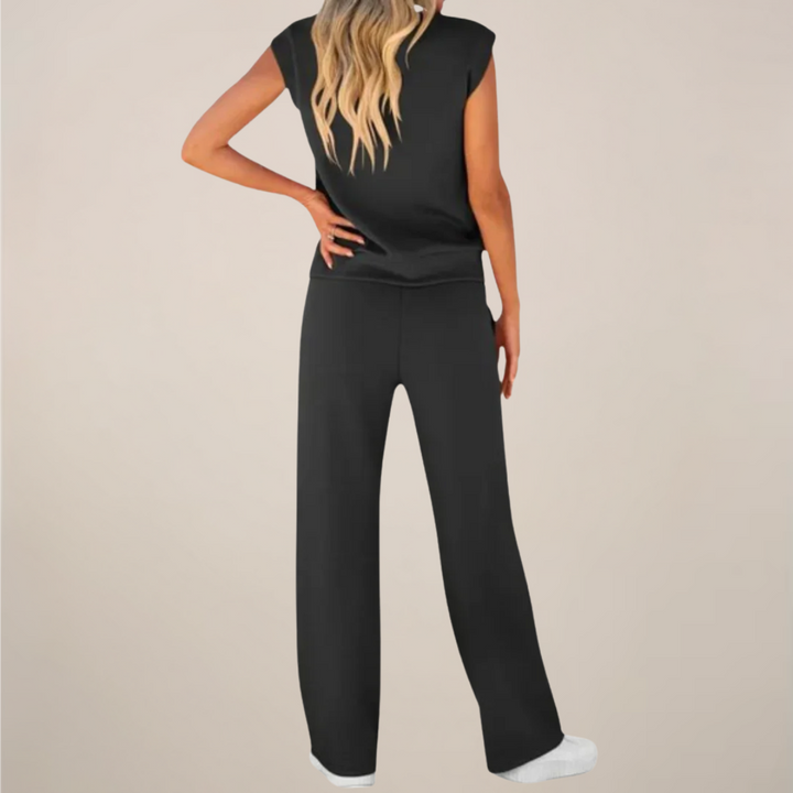 Woman in a casual two piece pants set standing against a plain background.