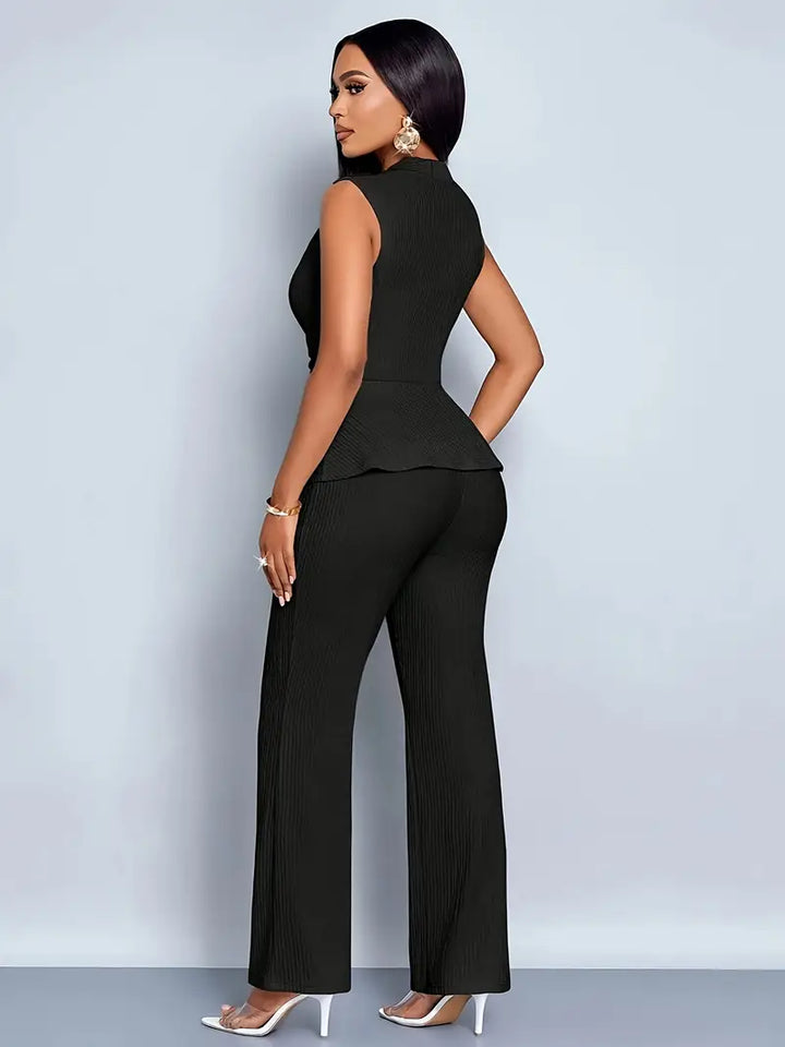 Female model in a polished peplum top and trouser set against a plain background.