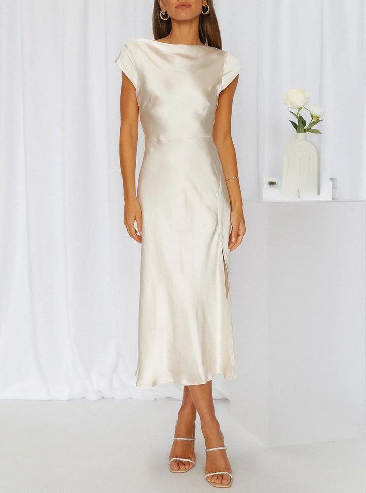 Female model showcasing a flowing midi dress with elegant styling on a plain background.