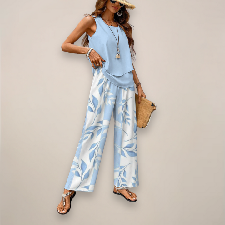 Woman in a flowy printed matching set with wide leg pants on a plain background.