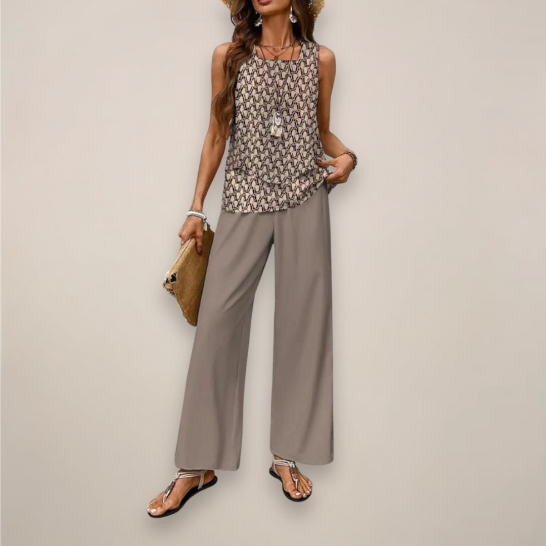 Woman in a printed wide leg pants set with a soft layered top on a plain background.