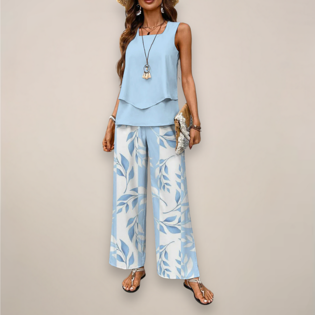Female model wearing a printed wide leg two piece set on a plain background.