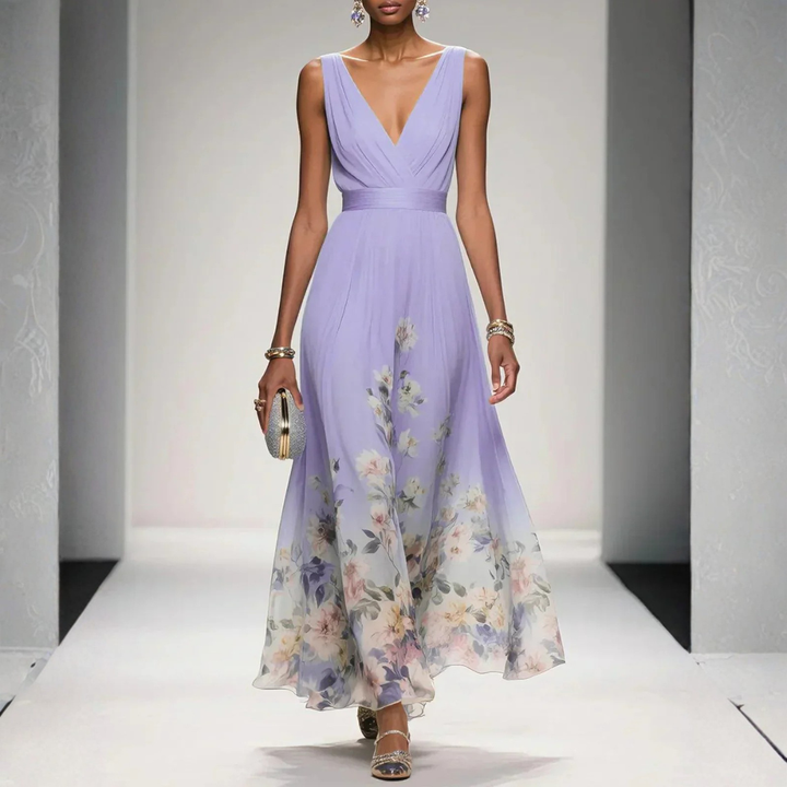 Female showcasing a sleeveless floral maxi dress with elegant drape on a plain background.