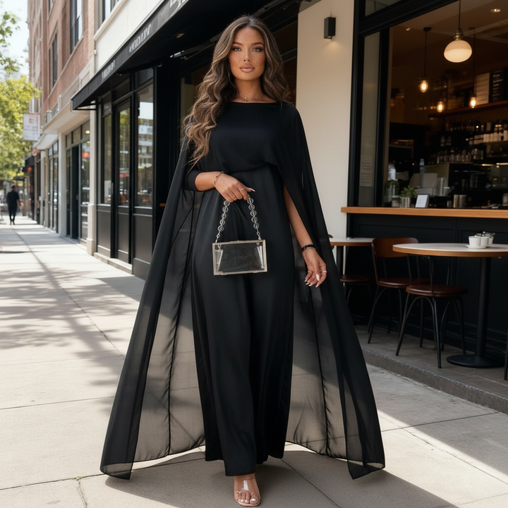 Model wearing a floor-length cape dress with a boat neckline on a plain background.