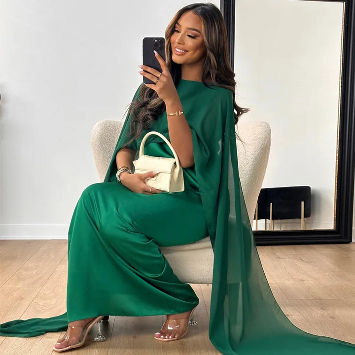 Female model wearing a long cape overlay dress on a plain background.