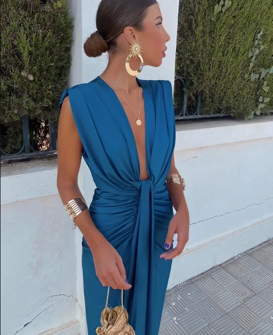 Female model in an elegant ruched evening dress on a plain background.