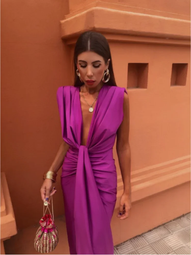Woman in a formal ruched maxi dress with fitted bodice on a plain background.