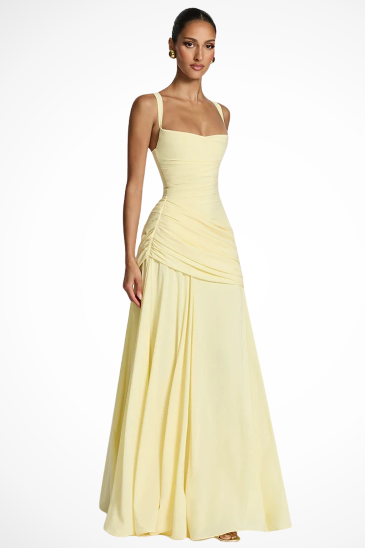 Female showcasing a fitted maxi dress with gathered bodice on a plain background.