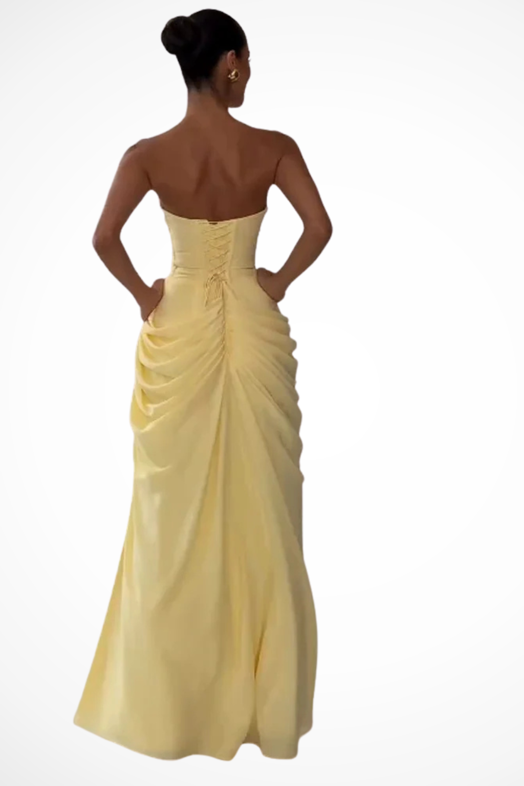 Woman posing in a floor-length strapless dress with side draping against a plain background.