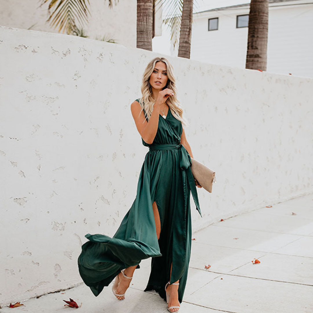 Model showcasing a long sleeveless occasion dress with adjustable waist detail on a plain background.
