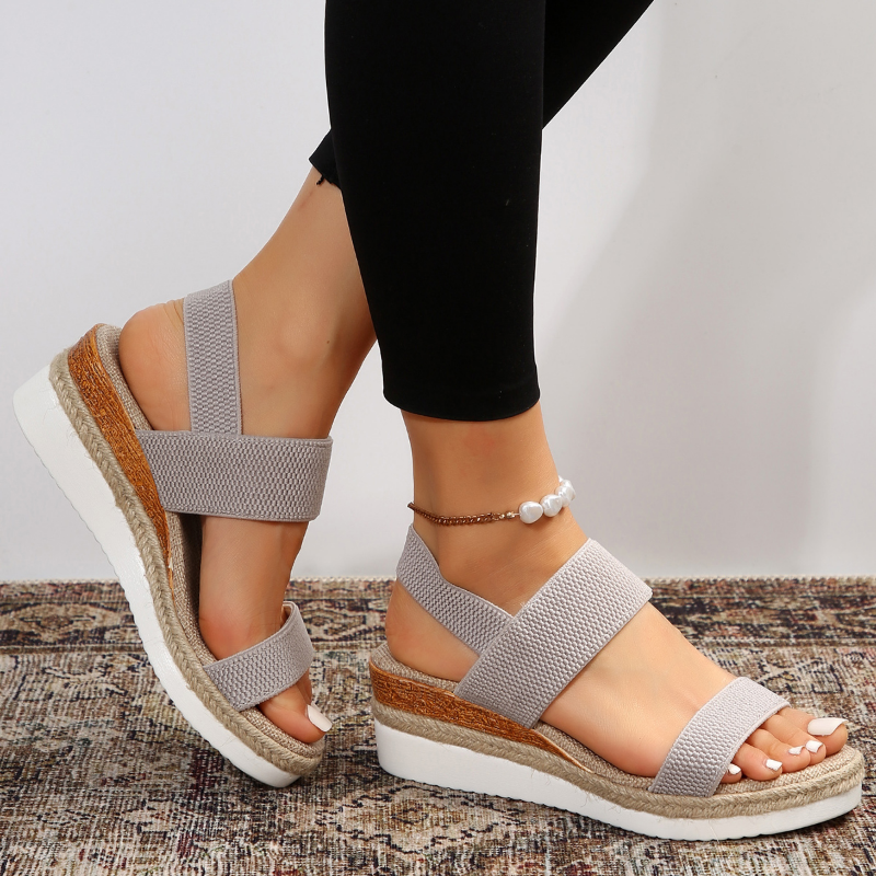 Female model showcasing versatile summer sandals on a plain background with simple styling.