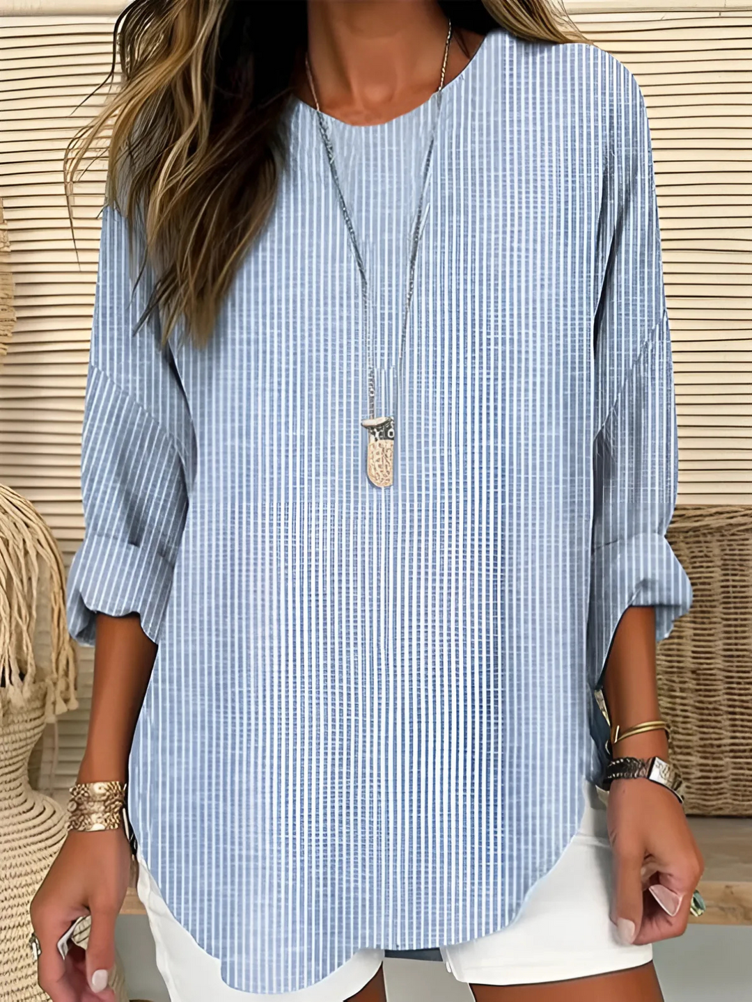 Woman wearing a striped blouse with a relaxed fit against a plain background.