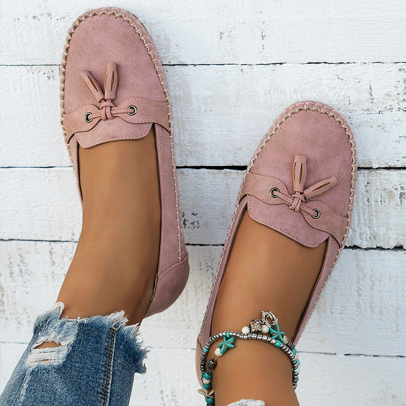 Women’s bow loafers with smooth finish on a plain background.