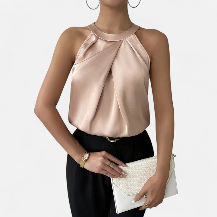 Woman wearing a pleated draped sleeveless tank on a plain background.
